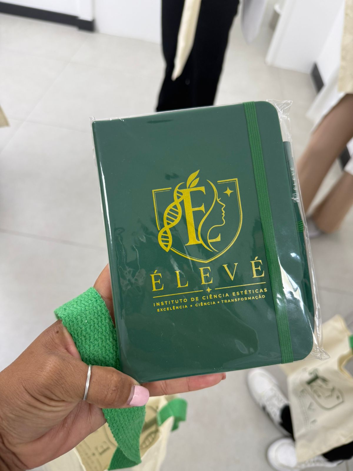 Caderno verde com o logo do Instituto ÉLEVÉ de Ciências Estéticas